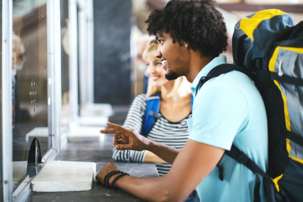 Young couple buying train tickets at ticket counter.