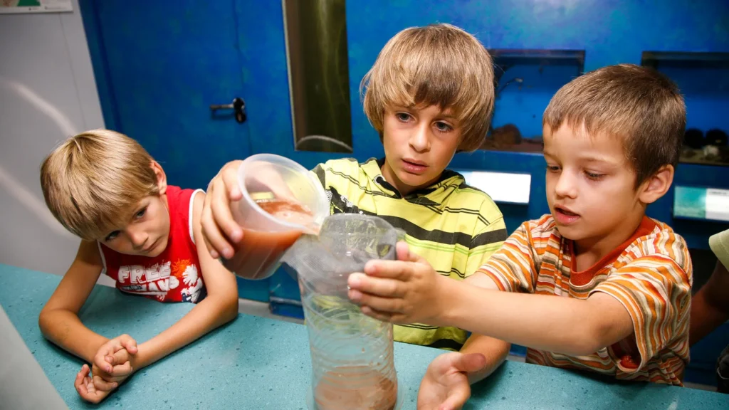 Alumnos realizan un experimento con arena y agua durante una actividad educativa sobre el entorno costero.